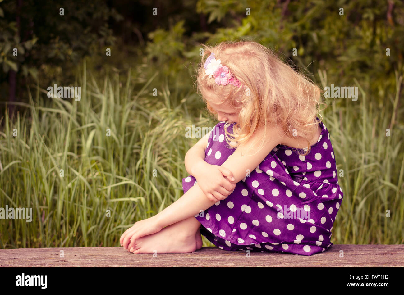 beautiful blond girl with closed eyes sitting on bench and posing Stock ...