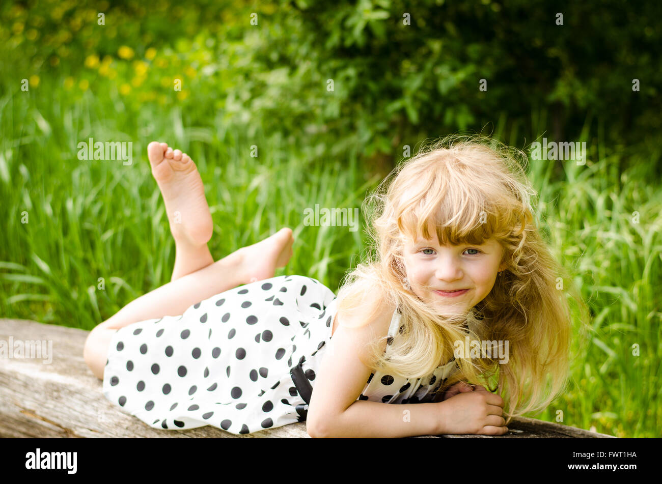 beautiful blond girl lying on wooden bench in meadow Stock Photo - Alamy