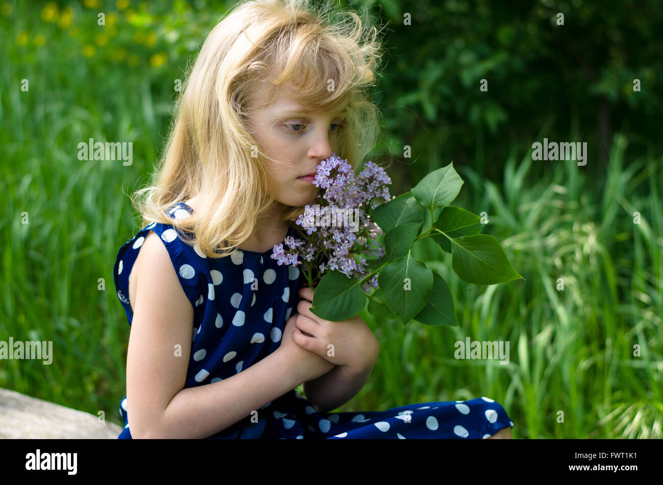 portrait of blond sad girl smelling flowers Stock Photo - Alamy