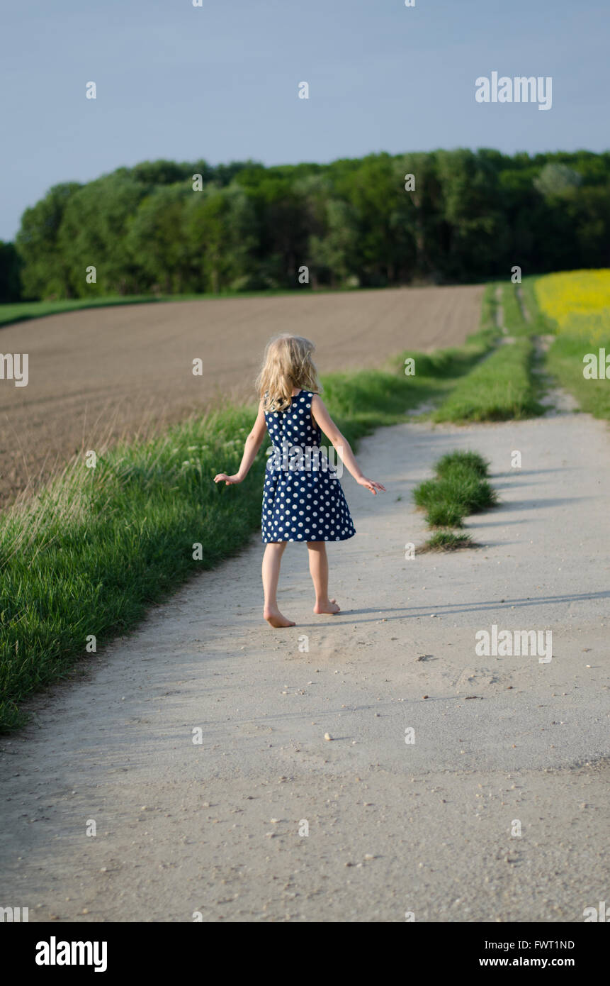 blond girl walking in path between fields Stock Photo - Alamy