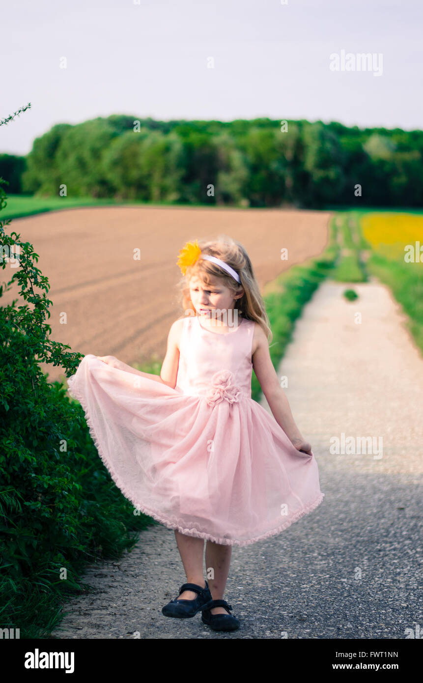 blond girl walking in path between fields Stock Photo