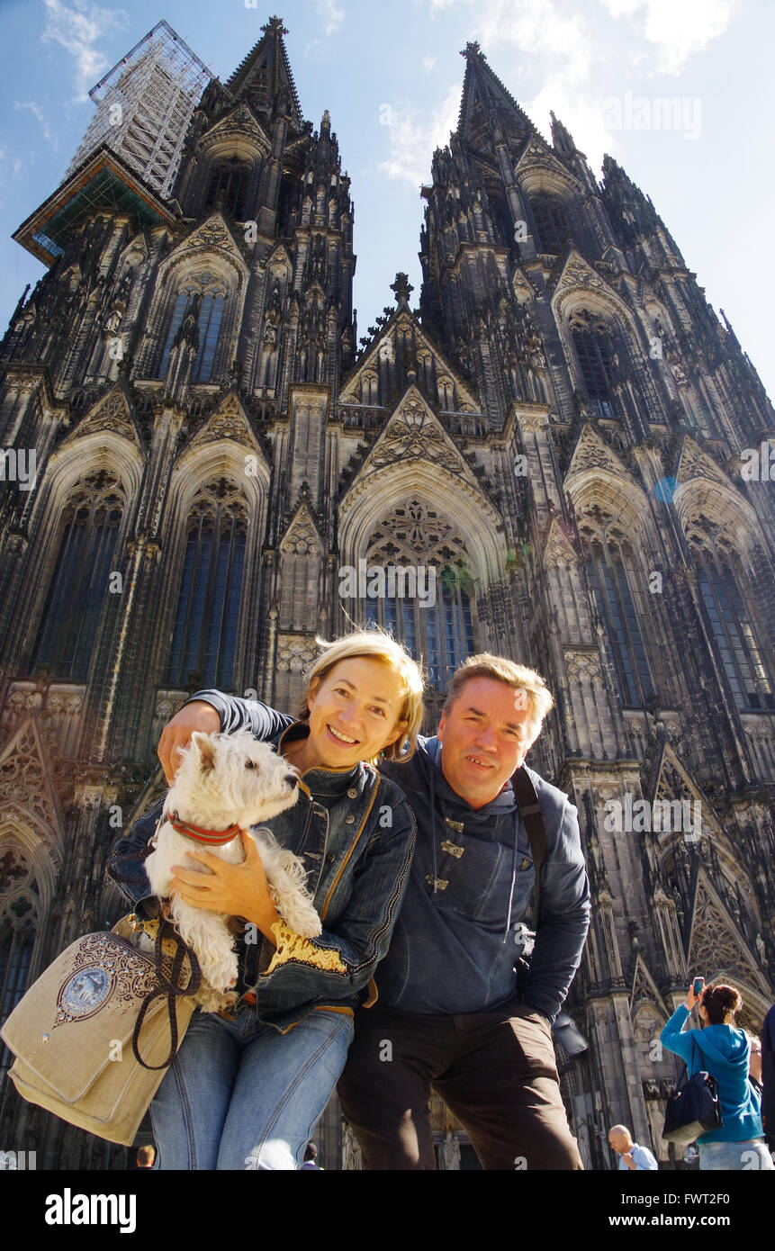 Happy couple posing with a dog in front of the Cologne (Köln) cathedral