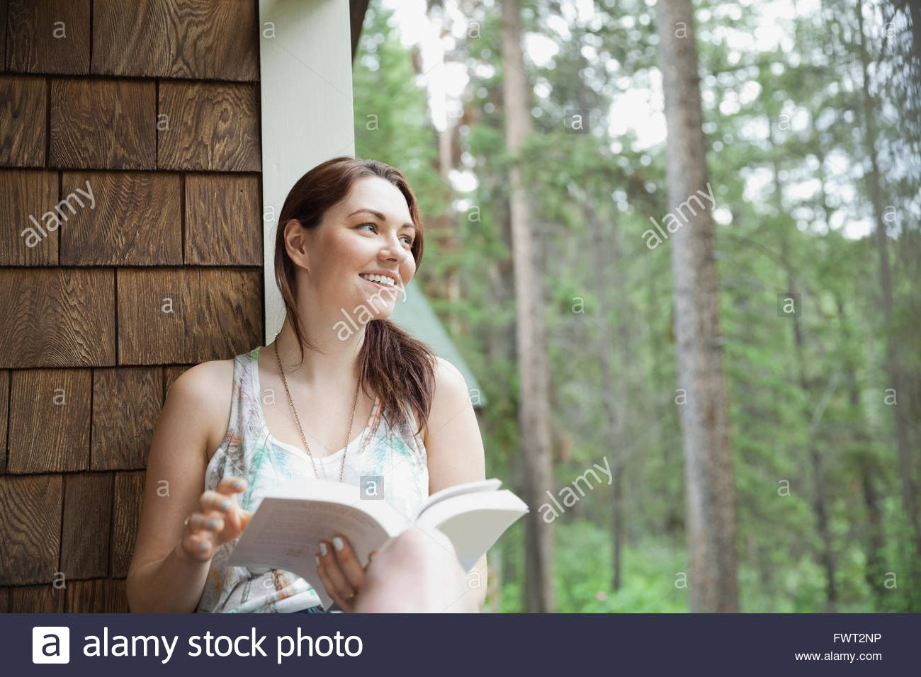 Woman sitting on cabin porch with book Stock Photo - Alamy
