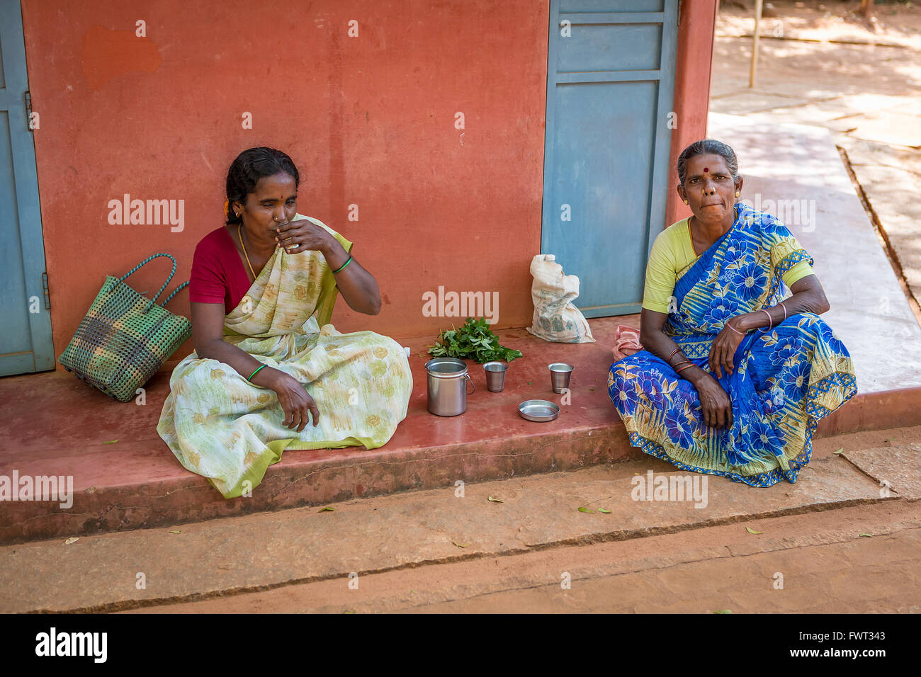 Two ladies eating and drinking on the route to the Matrimandir, at Auroville, in Viluppuram district in the state of Tamil Nadu Stock Photo