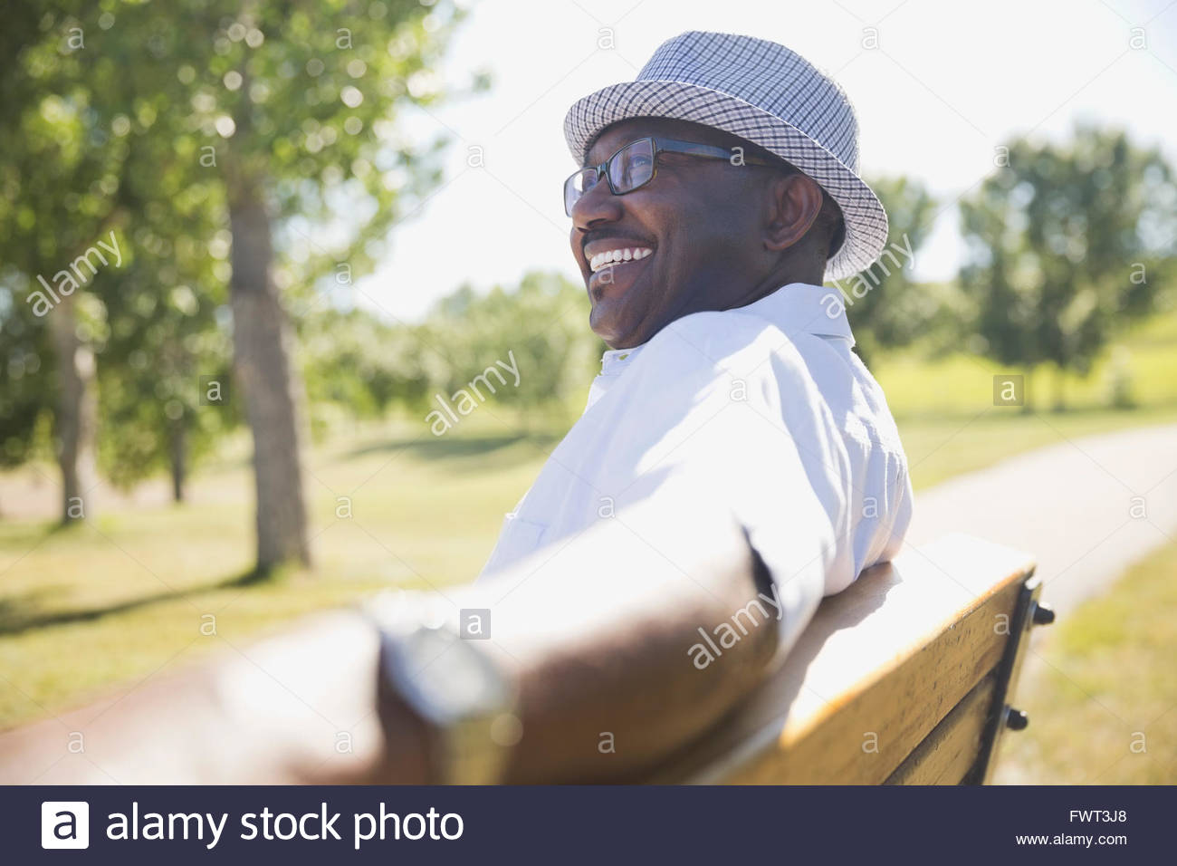 Smiling senior man sitting on park bench Stock Photo