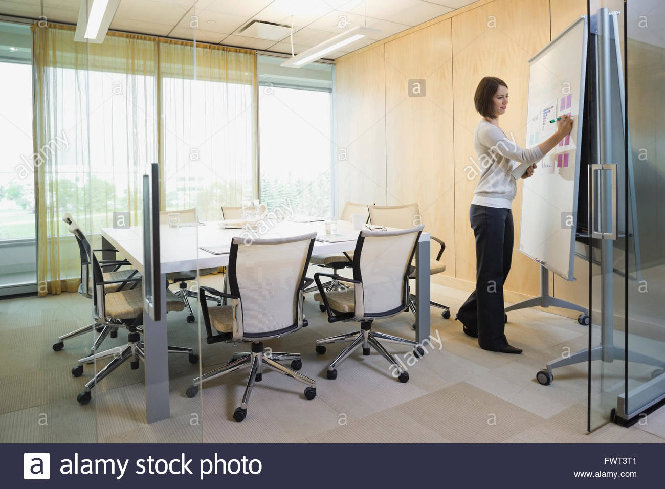 Businesswoman writing on flipchart in board room Stock Photo