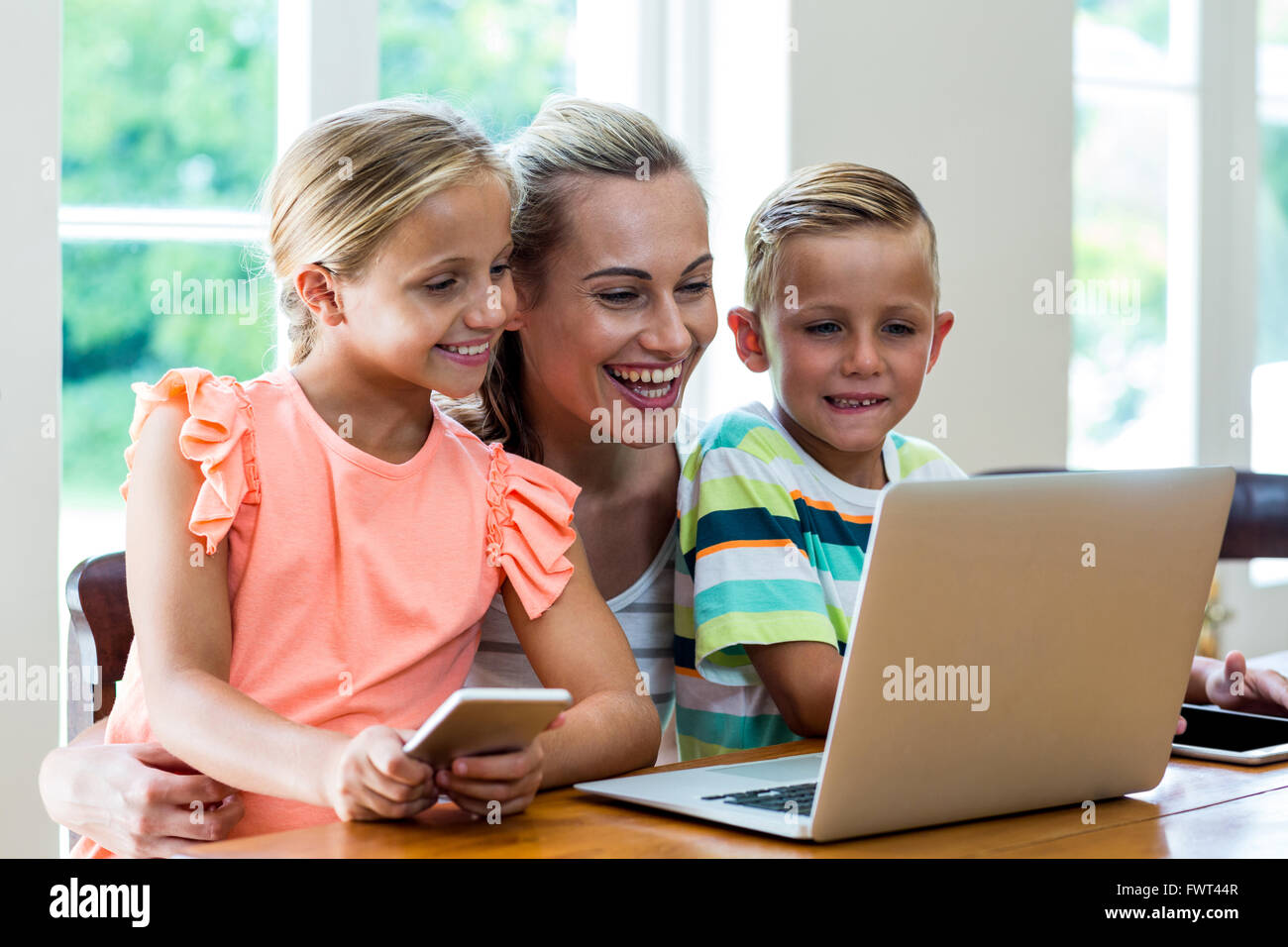 Smiling mother and children looking at laptop Stock Photo - Alamy