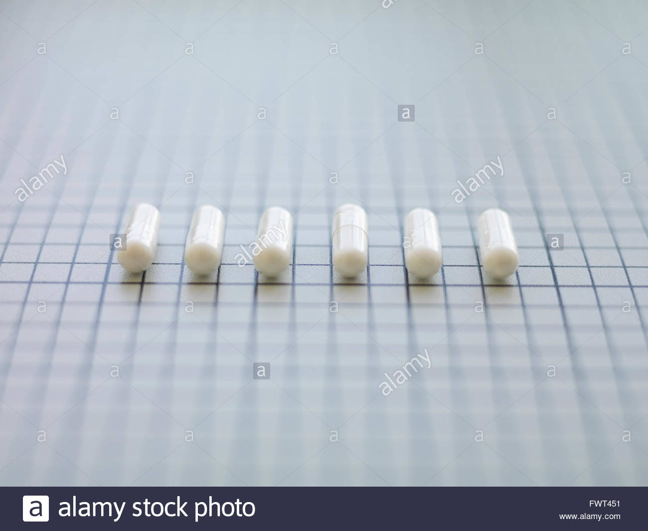 Capsules arranged side by side on table Stock Photo