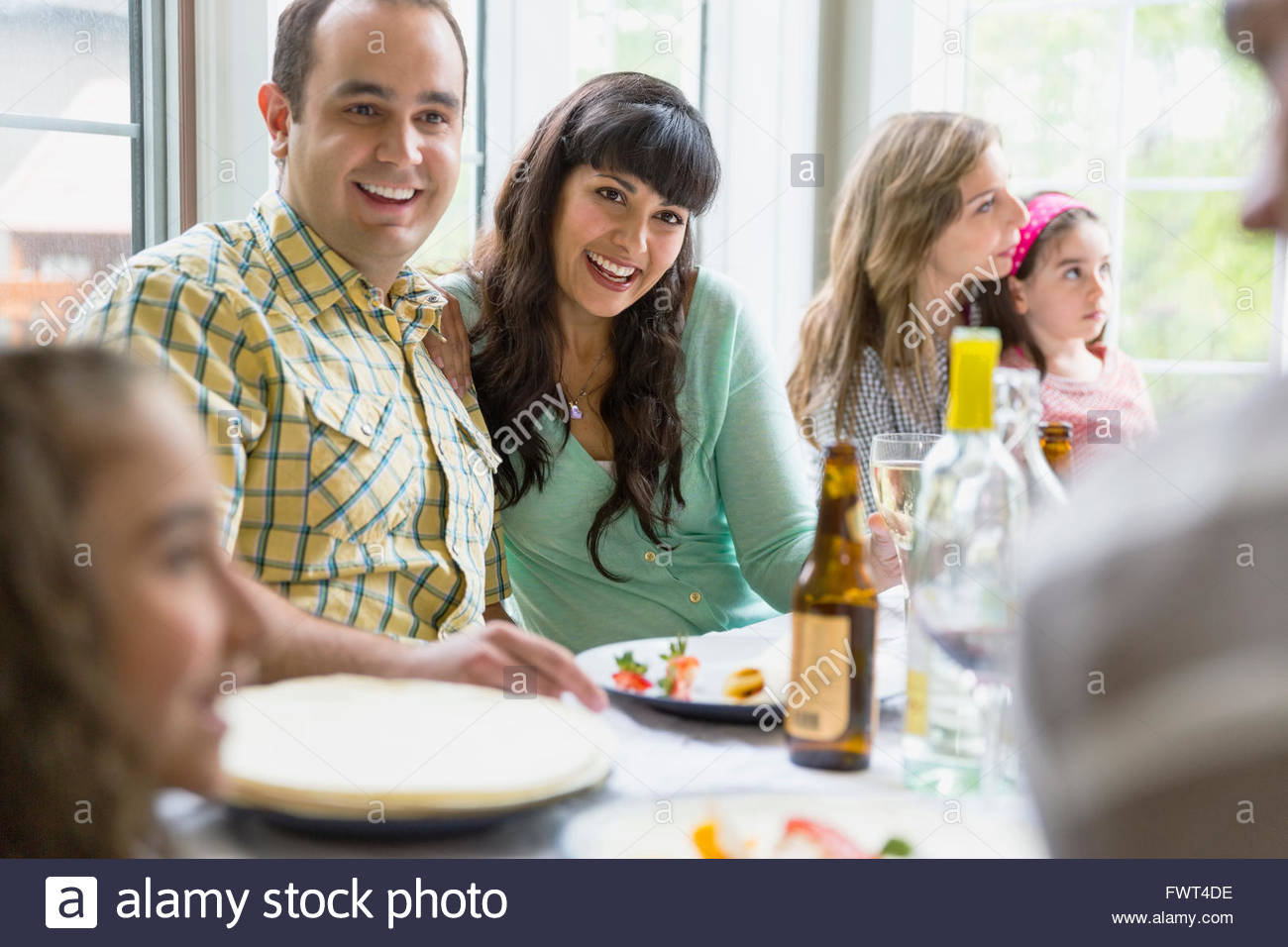 Cheerful couple sitting with family and friends at table Stock Photo