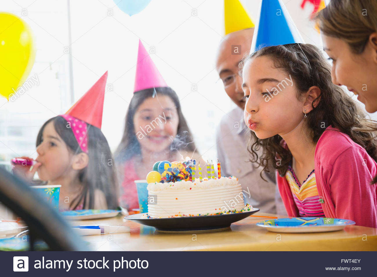 Little girl blowing out candles at birthday party Stock Photo Alamy