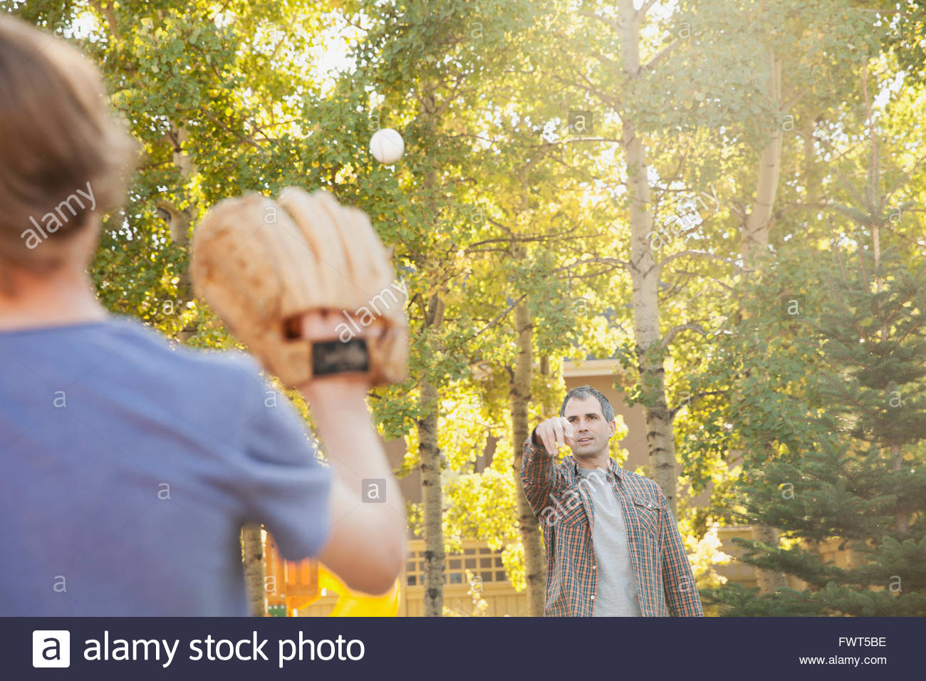 Father and son playing baseball in yard Stock Photo