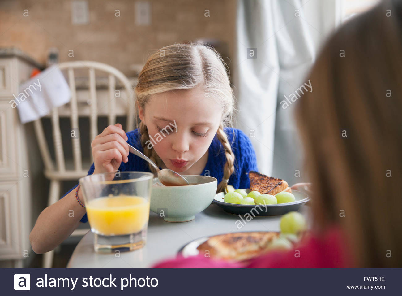 Young girl blowing on soup to cool it Stock Photo