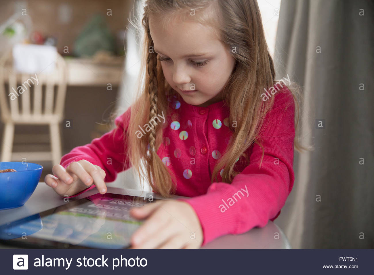 Cute young girl using digital tablet at table Stock Photo
