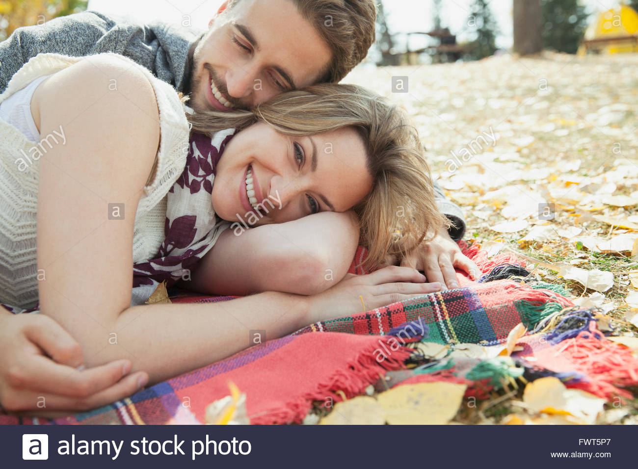 Couple cuddling on blanket in park Stock Photo Alamy