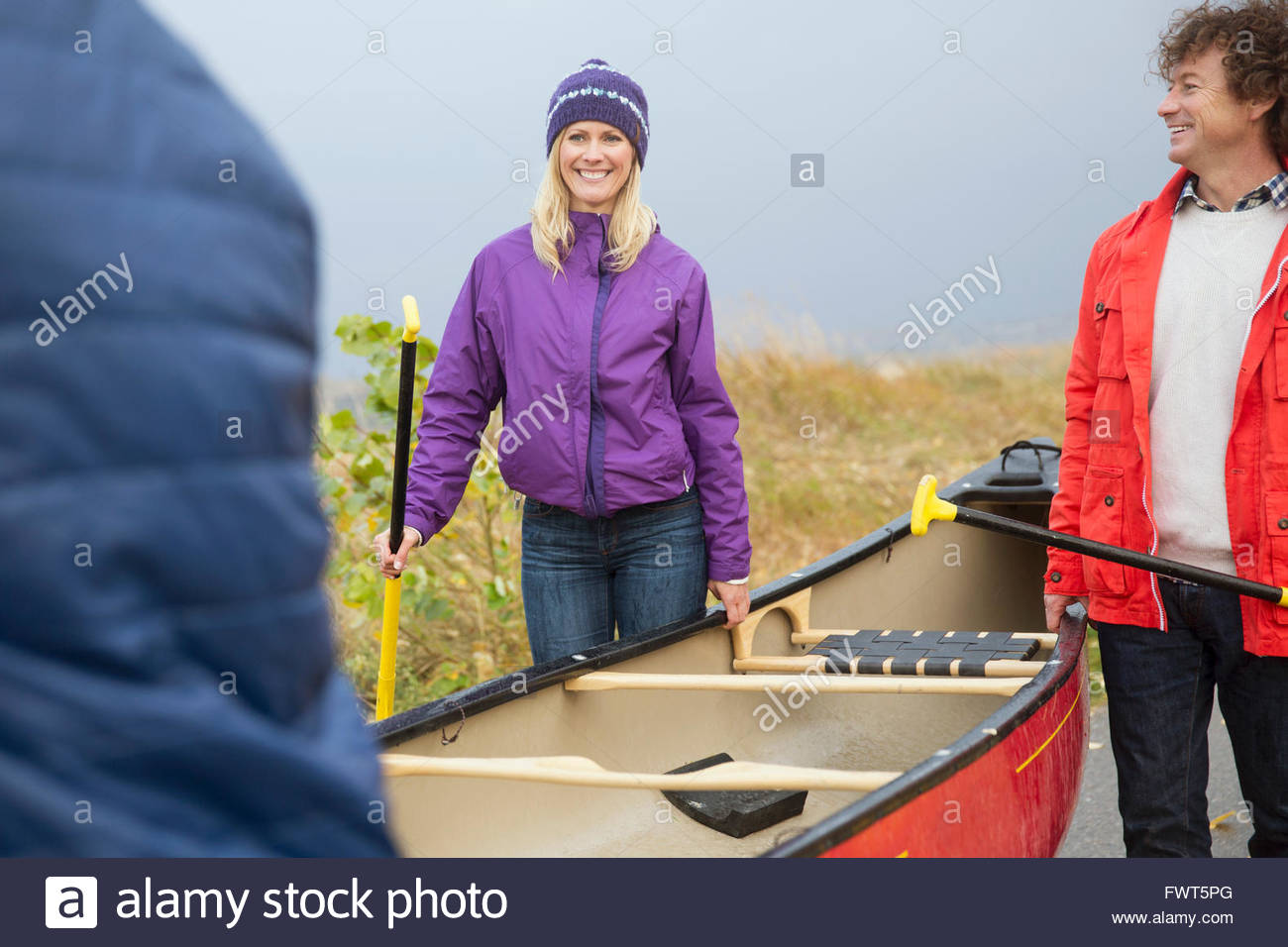 Friends carrying canoe and oars together Stock Photo Alamy