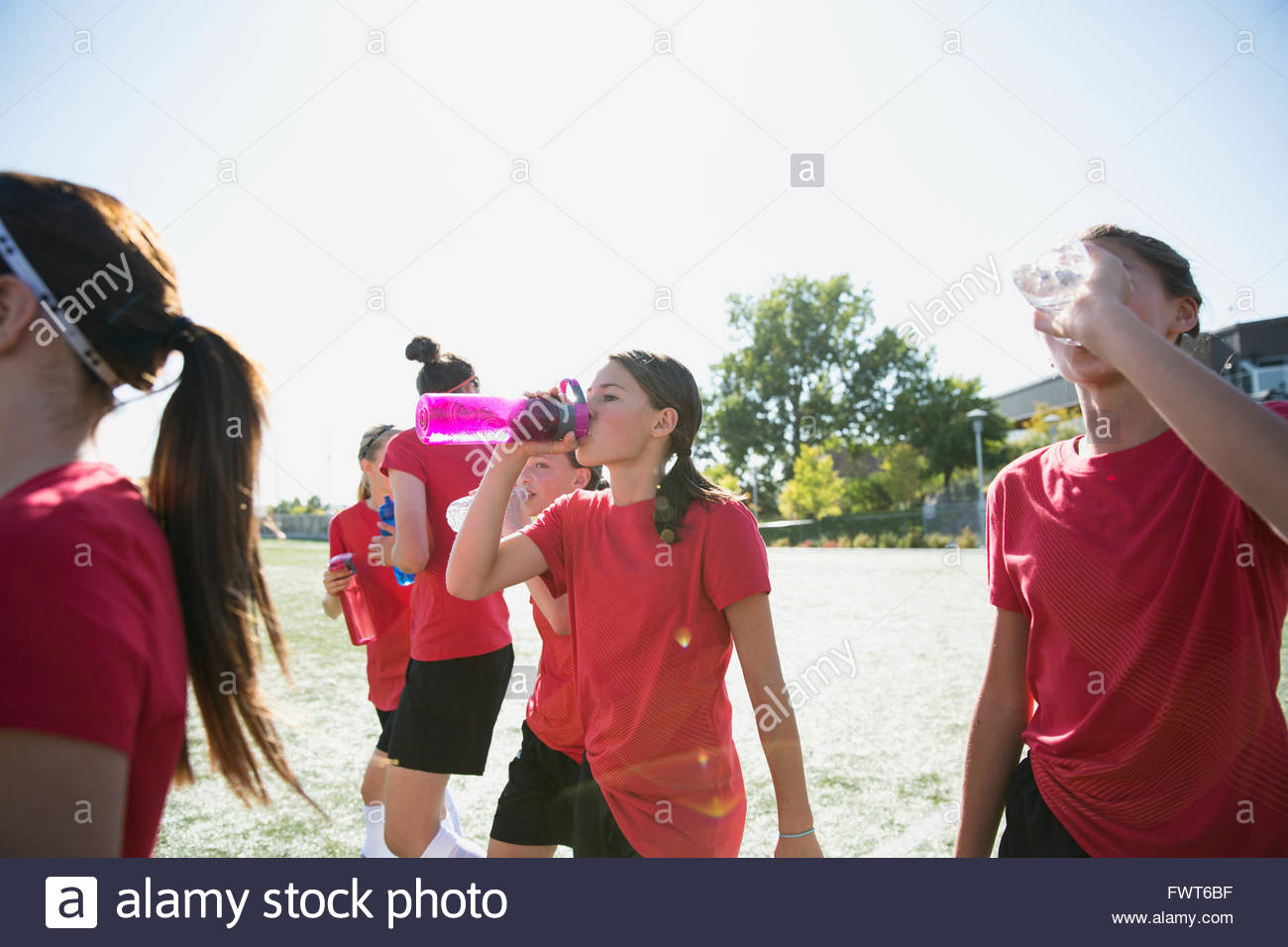 Girls soccer team drinking water on soccer field. Stock Photo