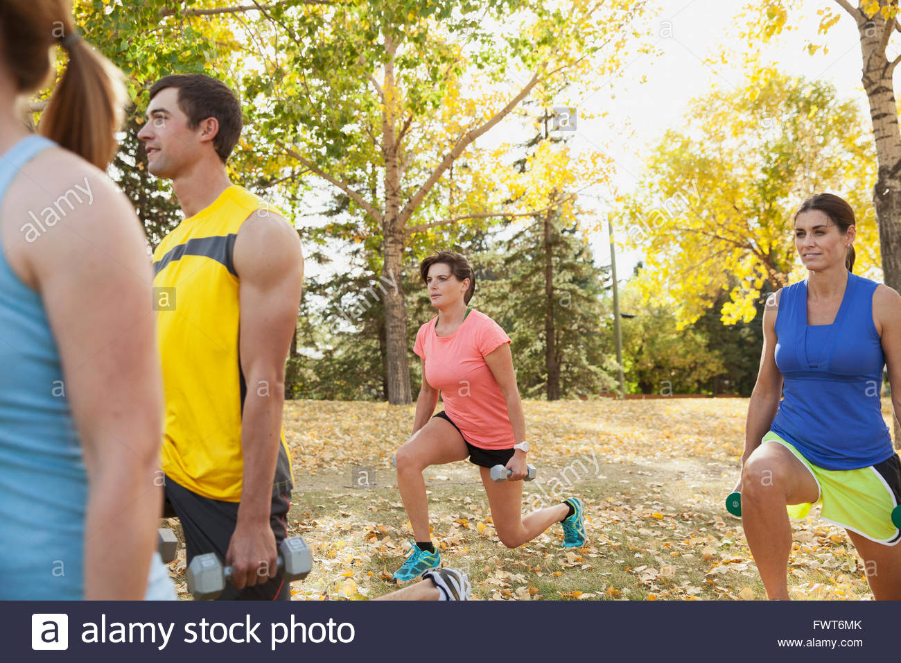 People using weights at outdoor fitness class. Stock Photo