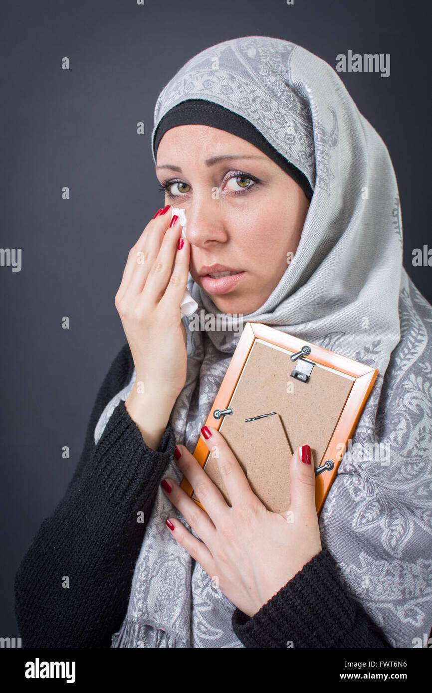 Muslim woman moaning over an old photograph in a frame Stock Photo