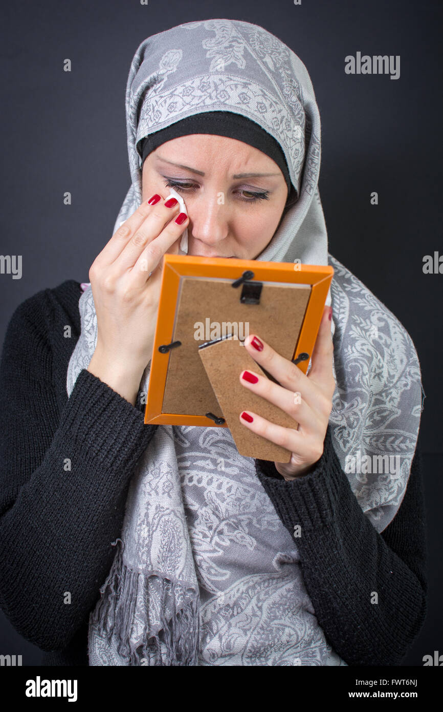 Muslim woman moaning over an old photograph in a frame Stock Photo