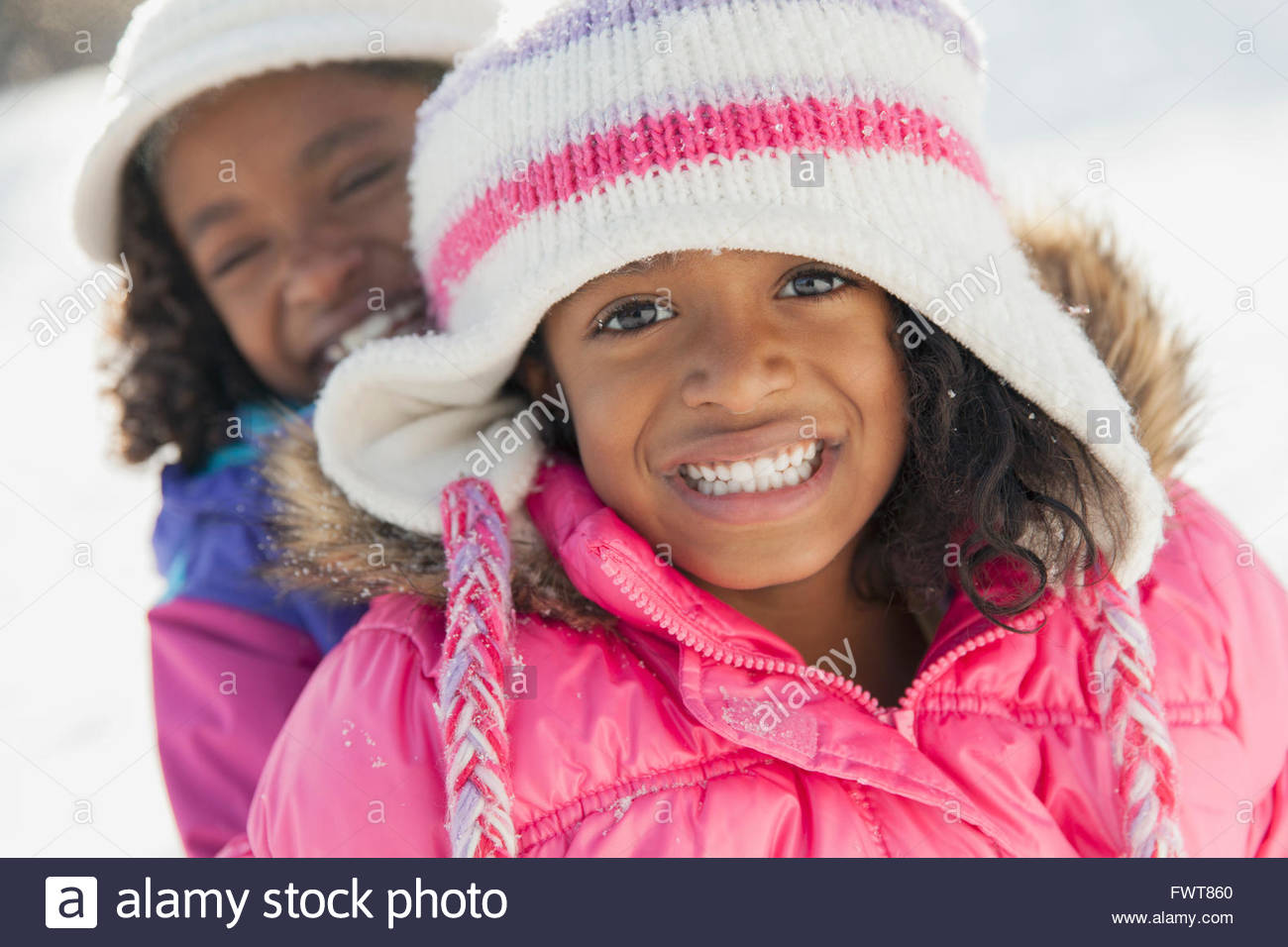 Portrait of happy little sisters smiling in snow Stock Photo