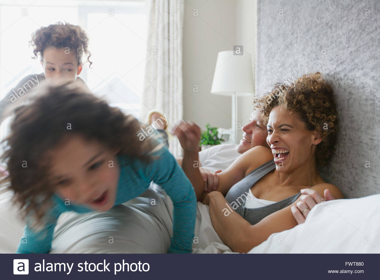 Daughters pouncing on parents bed Stock Photo Alamy