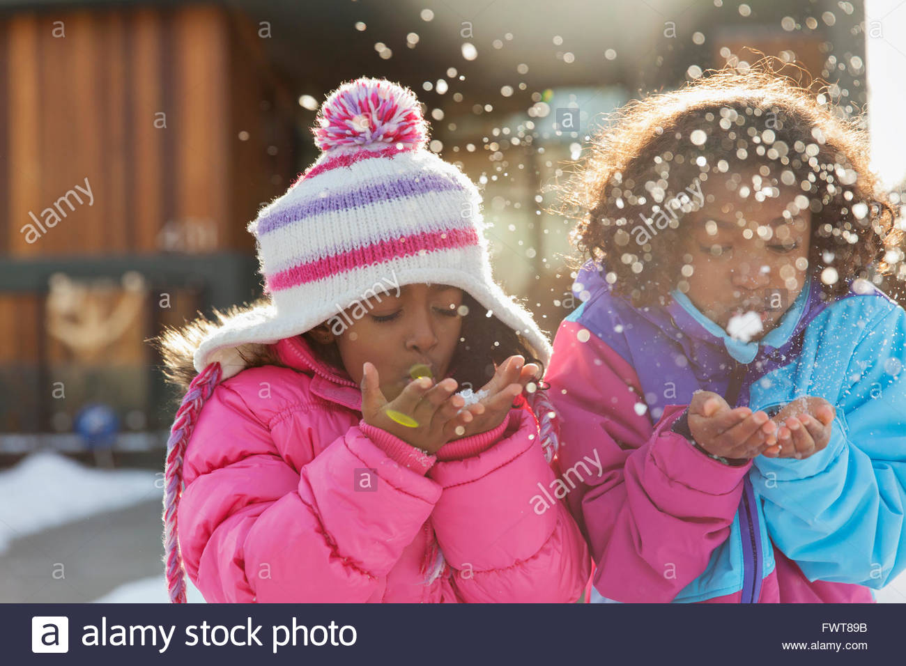 Cute little sisters blowing snowflakes outdoors Stock Photo