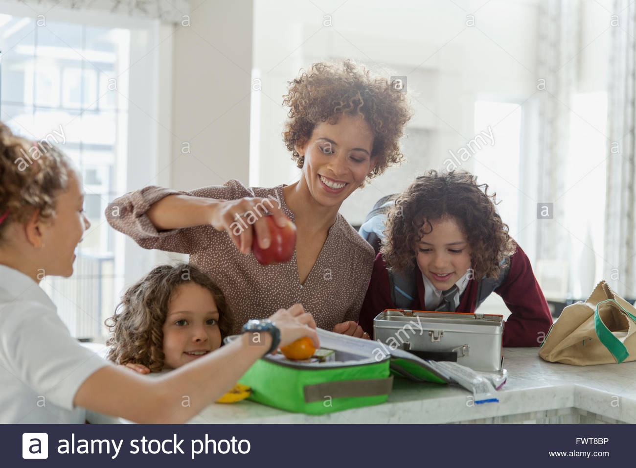 Mother helping daughters to pack lunches. Stock Photo