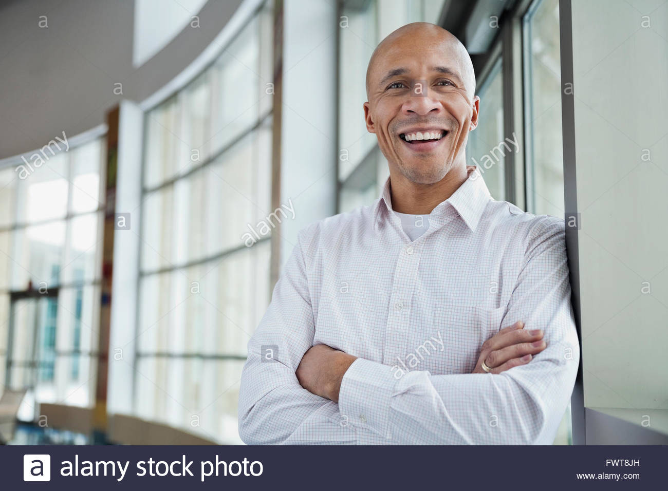 Happy businessman standing with arms crossed in office Stock Photo - Alamy