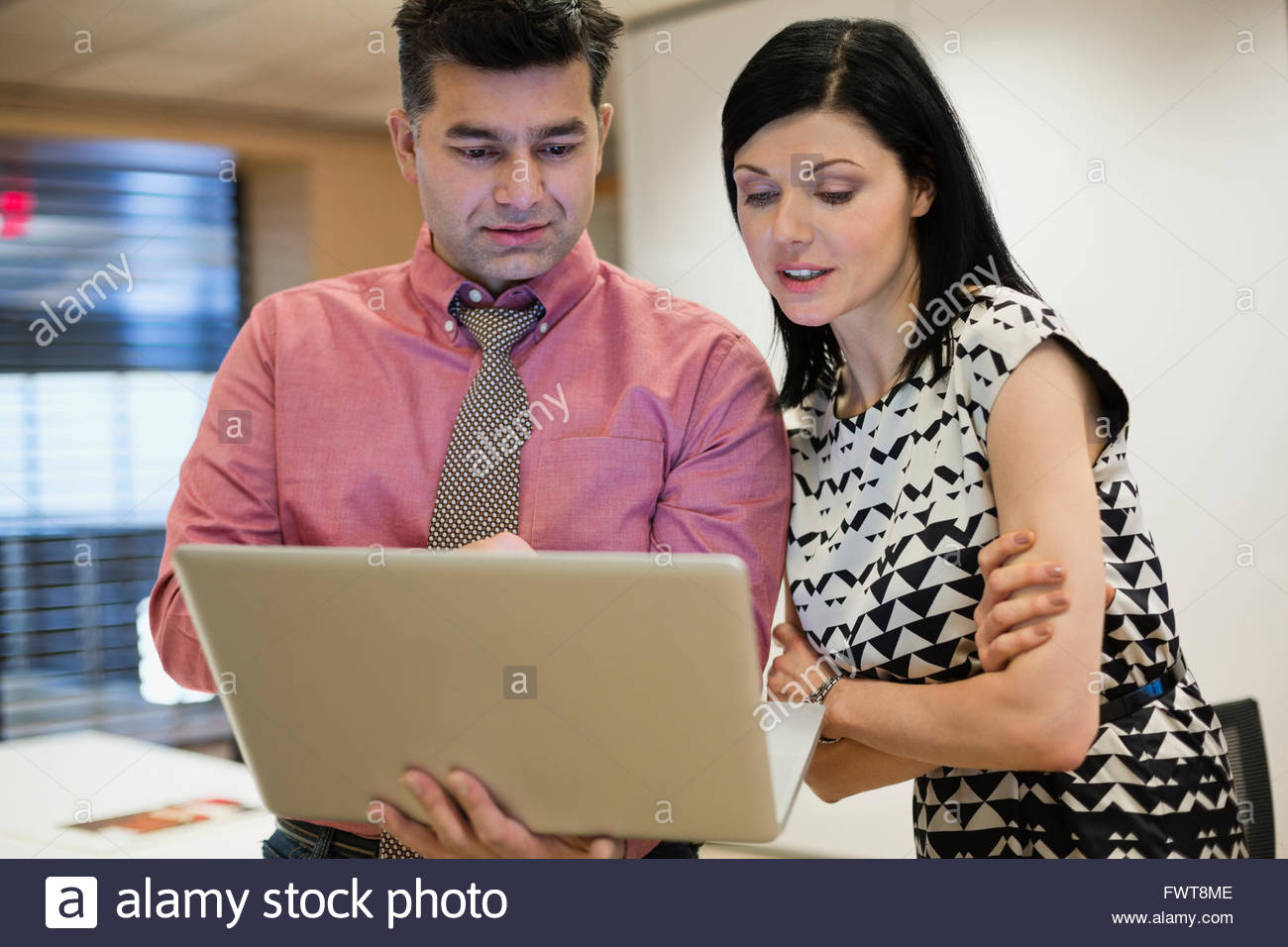 Businessman with female colleague using laptop in office Stock Photo