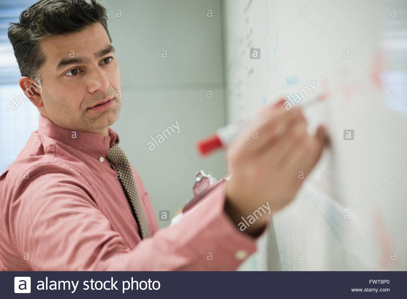 Businessman writing on whiteboard in board room Stock Photo