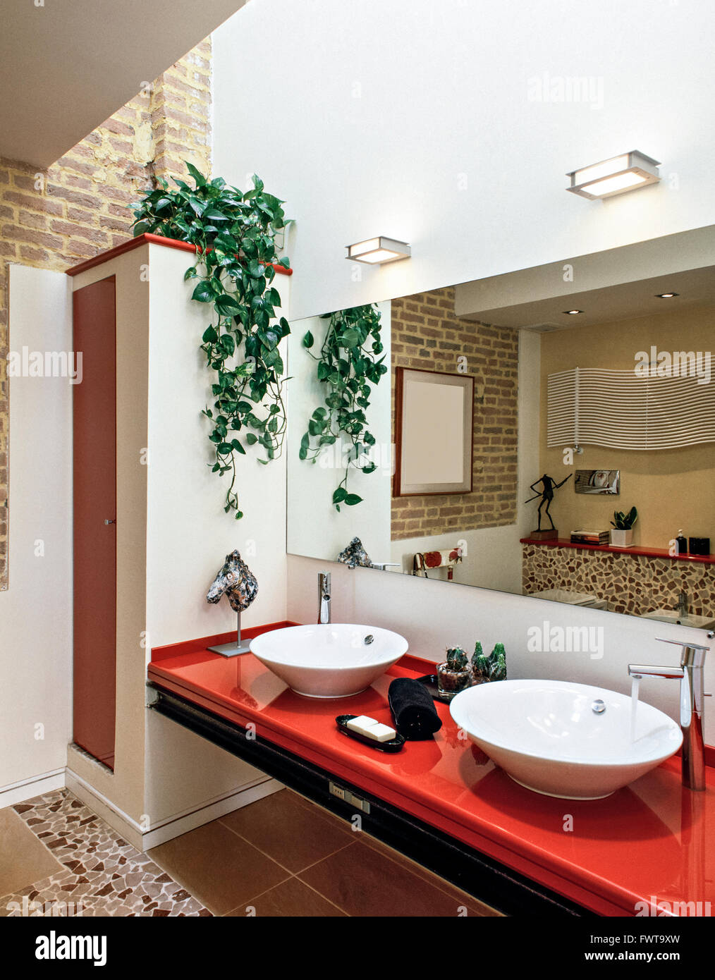 foreground of a red worktop with two washbasin  in a modern bathroom Stock Photo