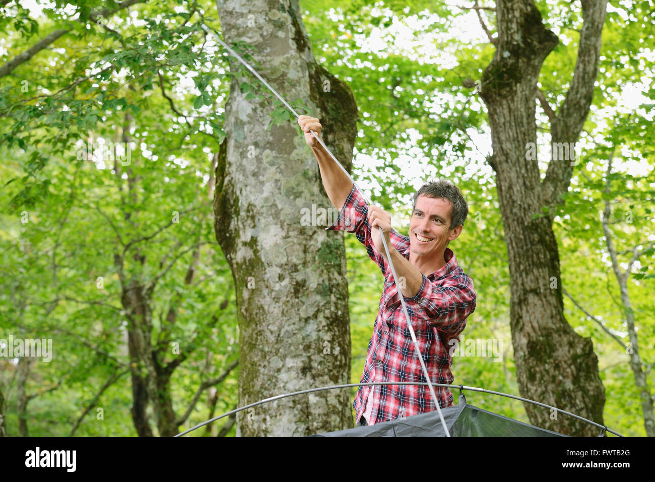 Caucasian man putting up a tent at a camp site Stock Photo