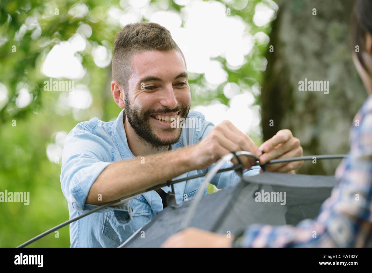 Friends putting up a tent at a camp site Stock Photo