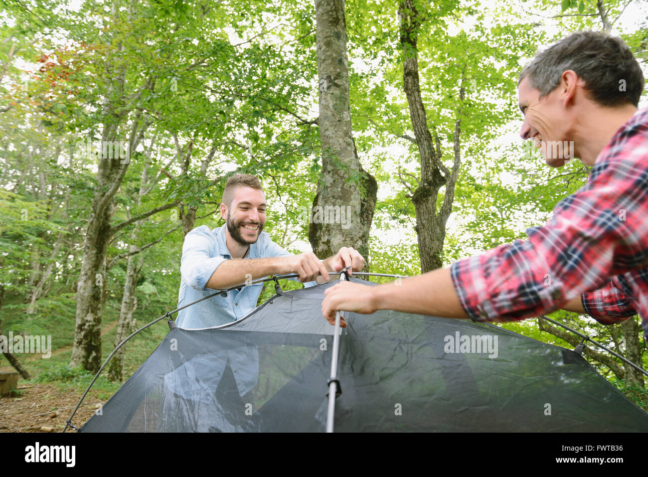 Friends putting up a tent at a camp site Stock Photo