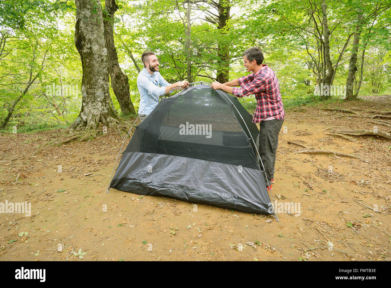 Friends putting up a tent at a camp site Stock Photo