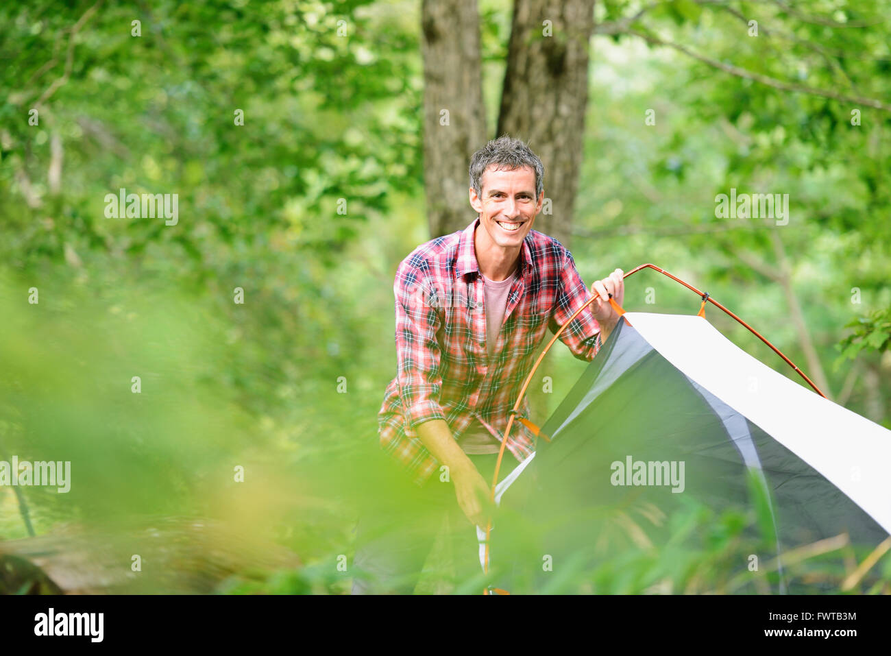 Caucasian man putting up a tent at a camp site Stock Photo