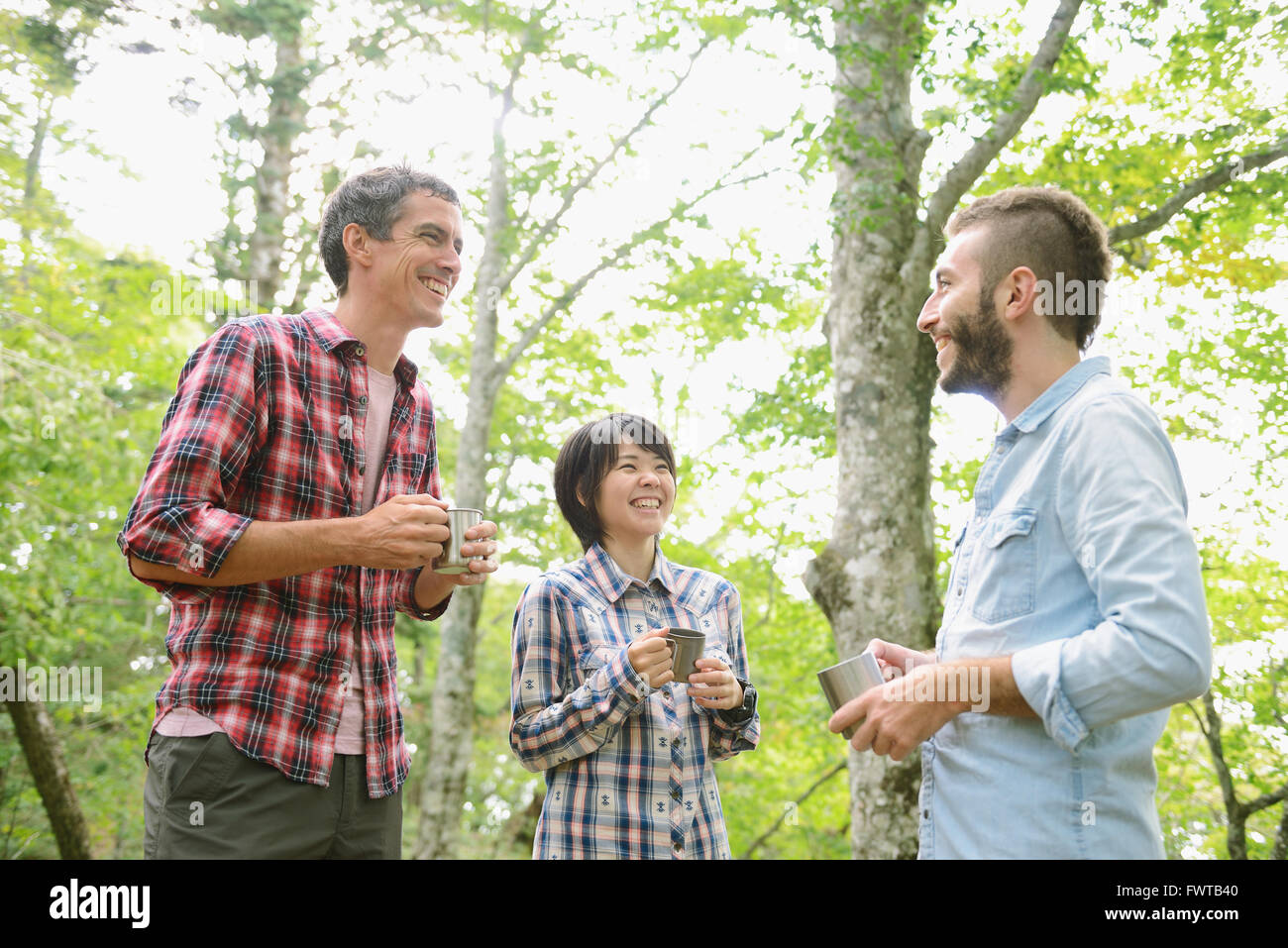 Multi-ethnic group of friends having coffee at a camp site Stock Photo