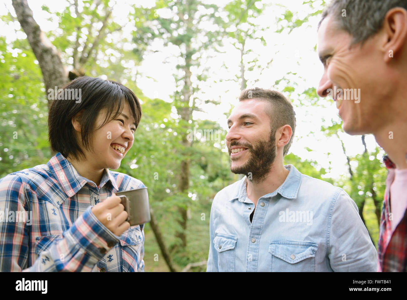 Multi-ethnic group of friends having coffee at a camp site Stock Photo