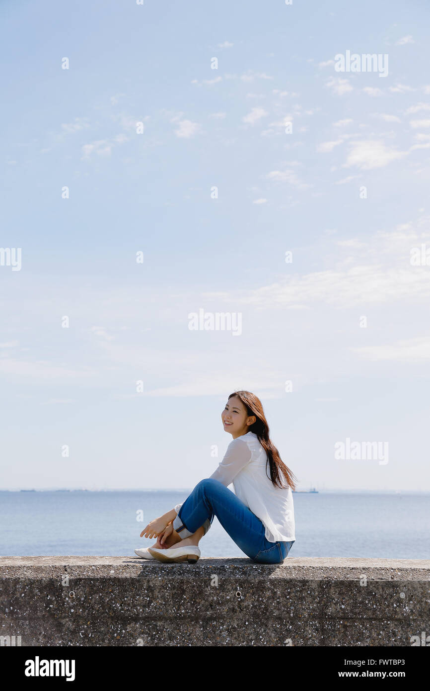Young woman sitting wall hi-res stock photography and images - Alamy