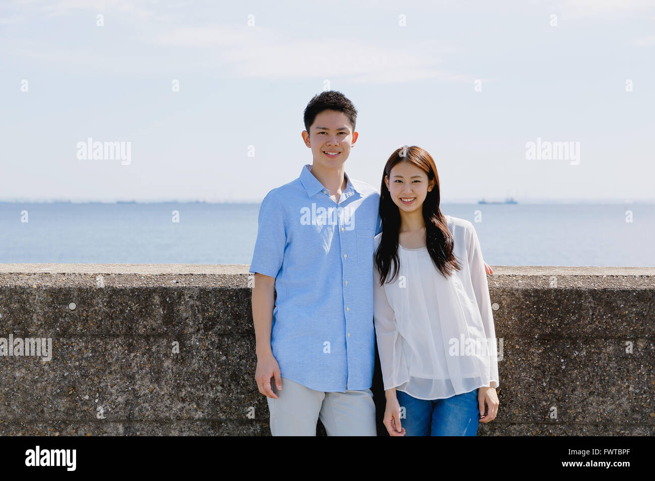 Young Japanese couple leaning on concrete wall by the sea Stock Photo ...