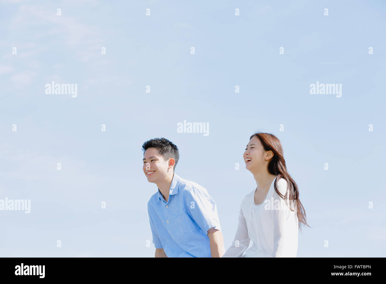 Young Japanese couple sitting on concrete wall by the sea Stock Photo ...