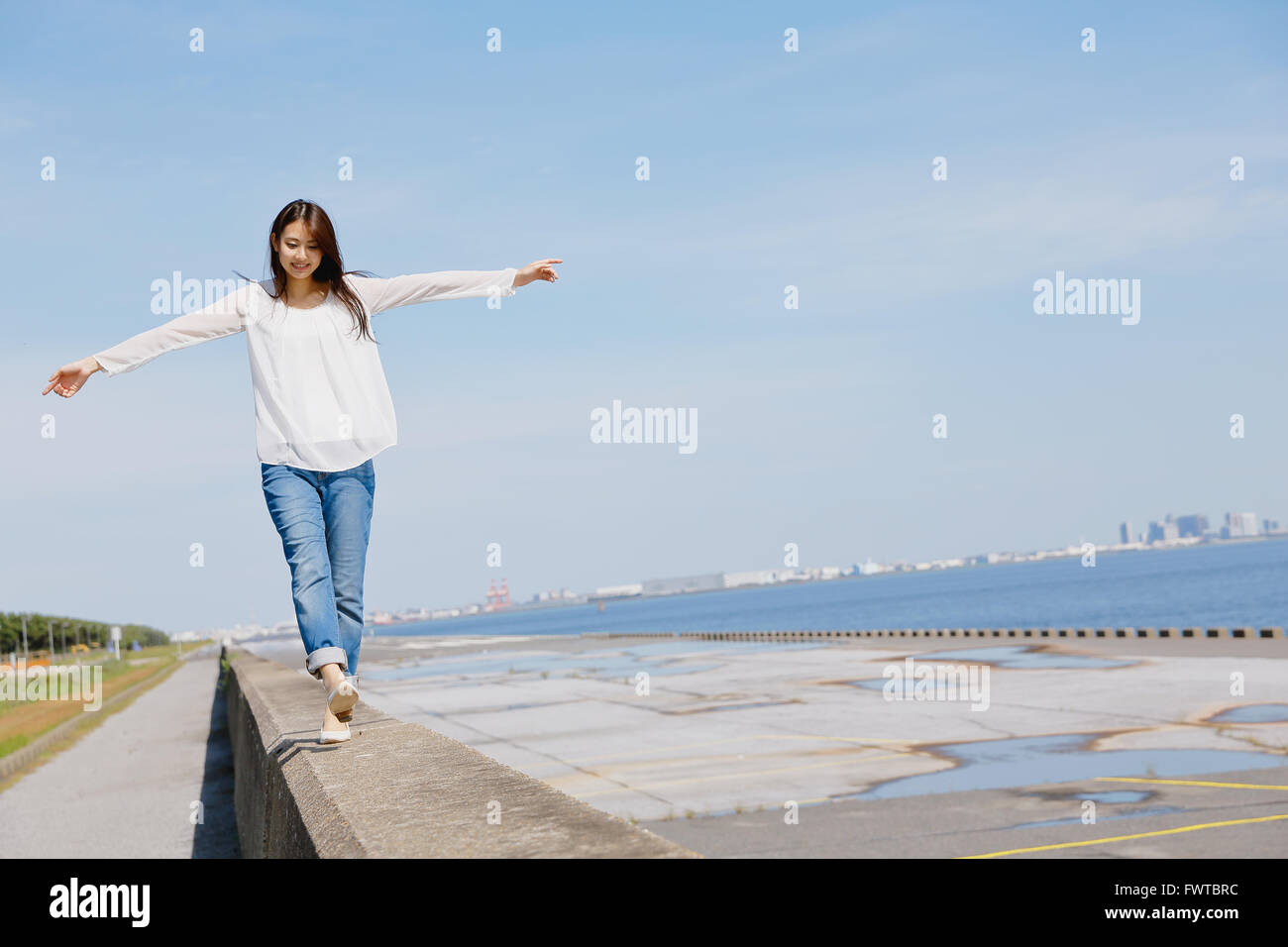 Young Japanese woman standing on concrete wall by the sea Stock Photo ...