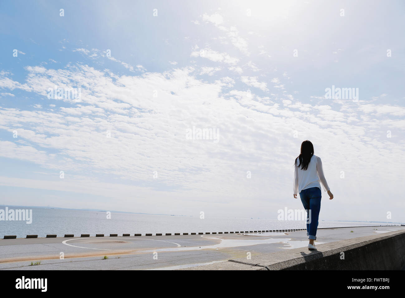 Young Japanese woman standing on concrete wall by the sea Stock Photo ...