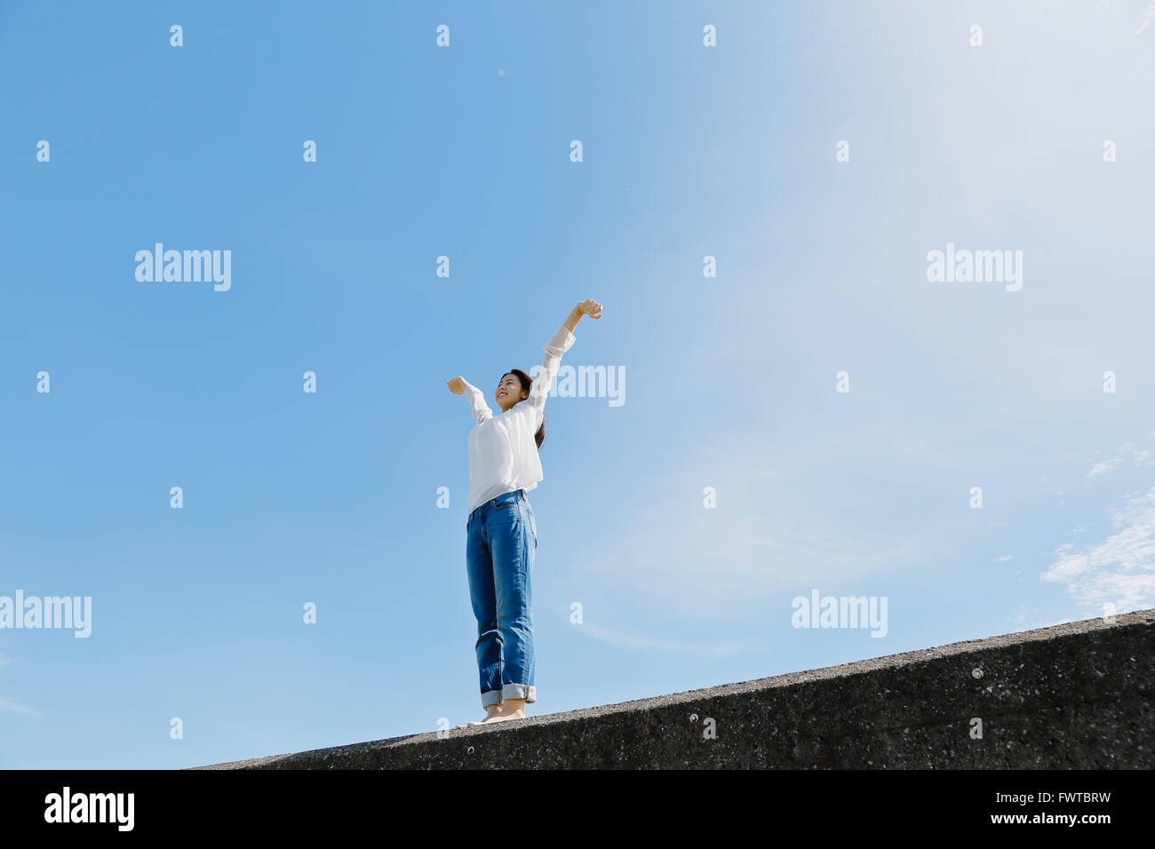 Young Japanese woman standing on concrete wall by the sea Stock Photo ...