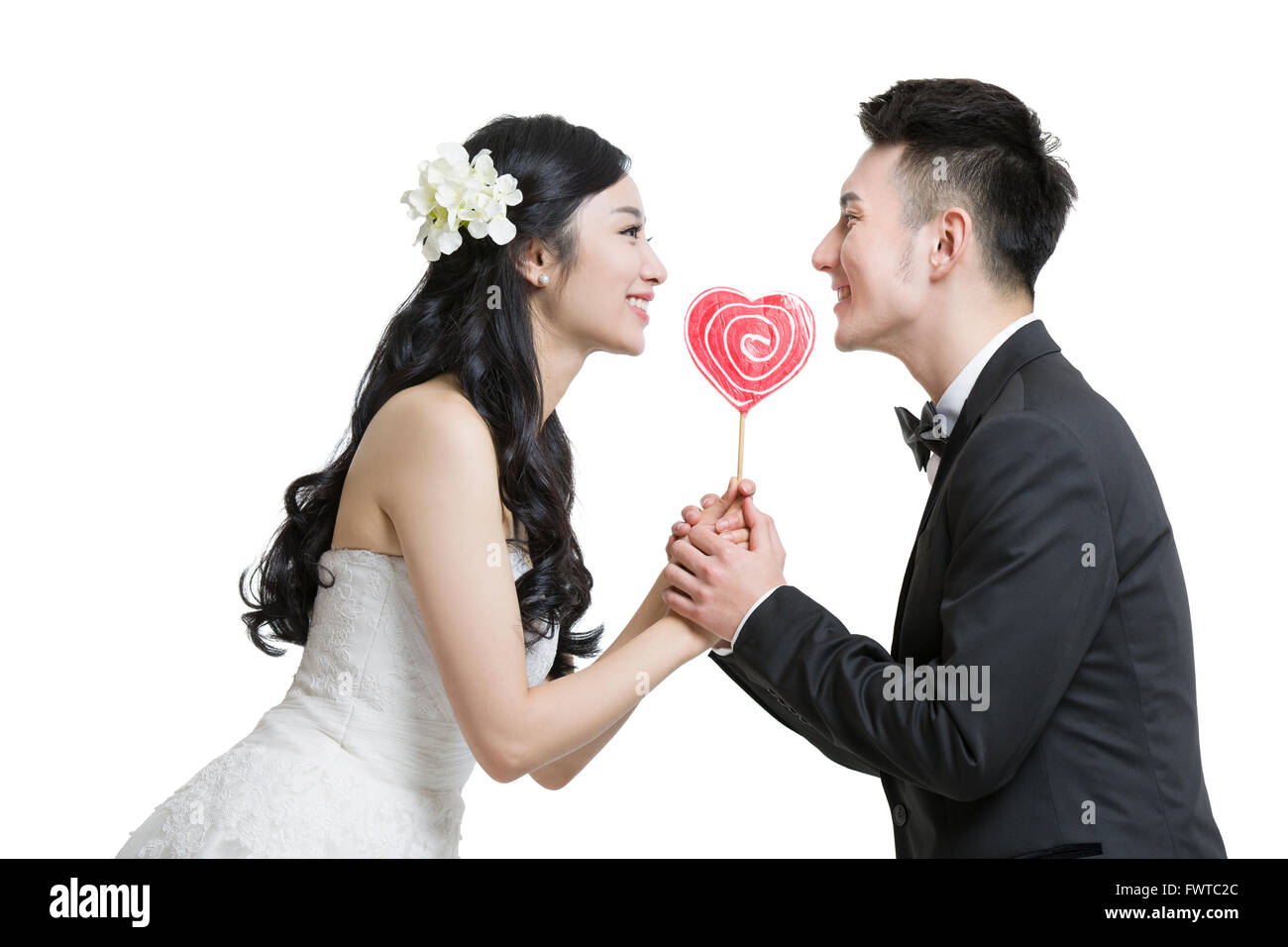 Happy bride and groom holding a heart-shaped lollipop Stock Photo