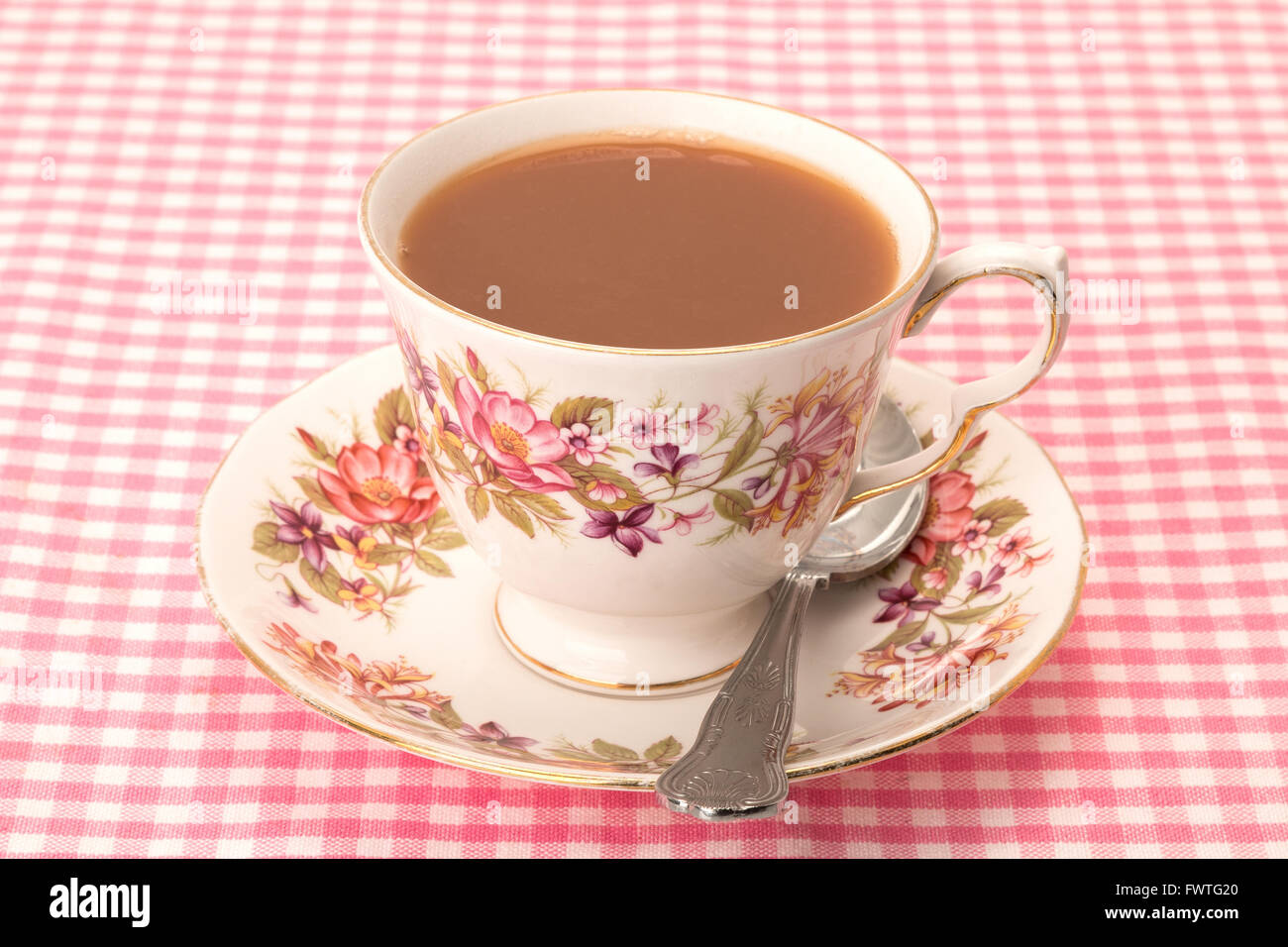 A hot cup of tea served in an antique patterned tea cup and saucer, all