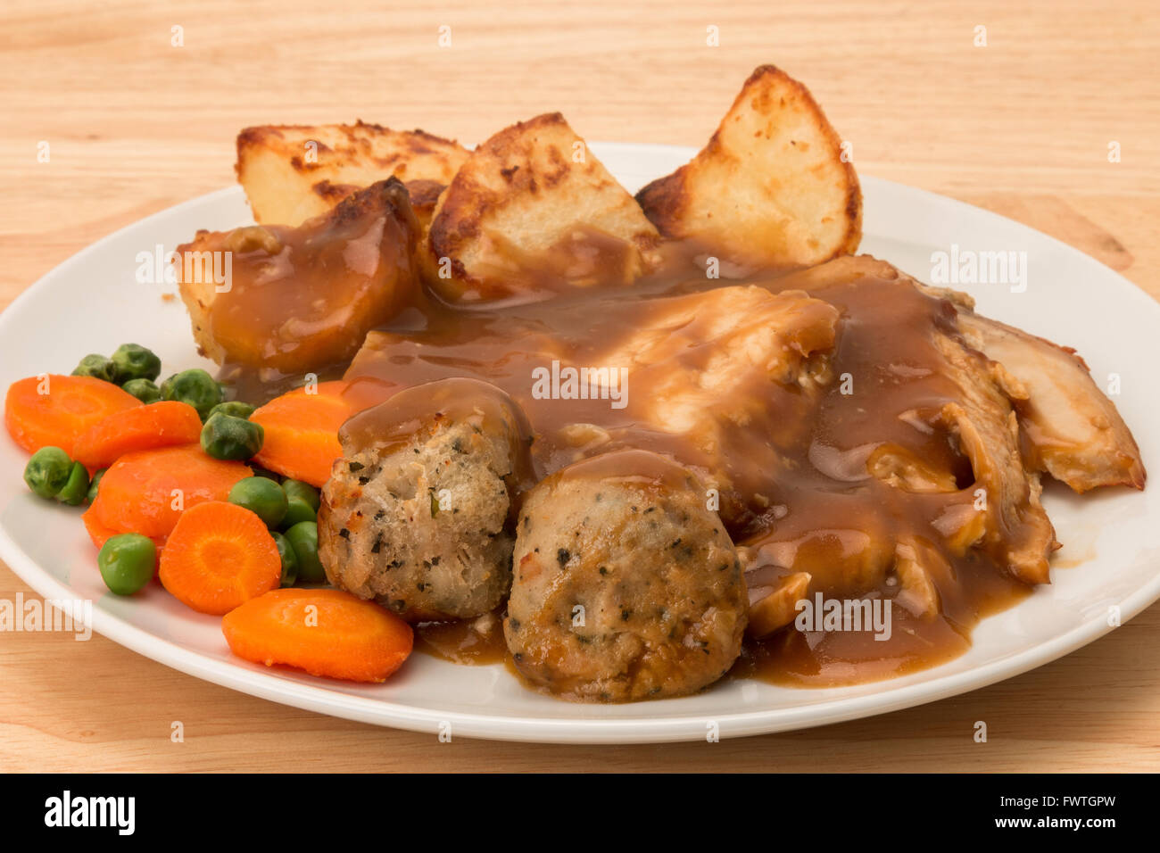 A roasted chicken dinner with carrot and peas, sage and onion stuffing balls, and gravy Stock