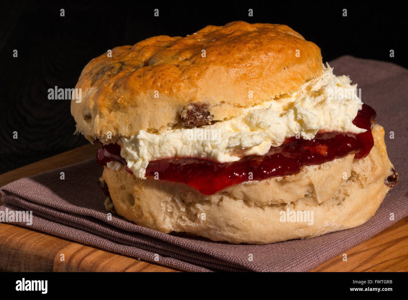 Freshly baked and served scone packed full of delicious strawberry jam and Cornish clotted cream Stock Photo