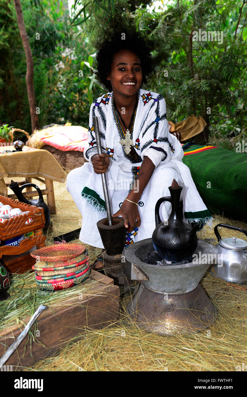 A young Ethiopian woman grinding the coffee beans during a traditional