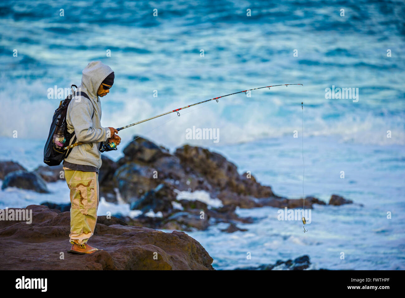 local man fishing off rocky coast Ho'okipa Beach Park Maui Hawaii Stock Photo